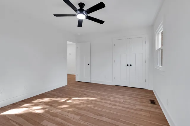 a view of a bedroom with wooden floor and window