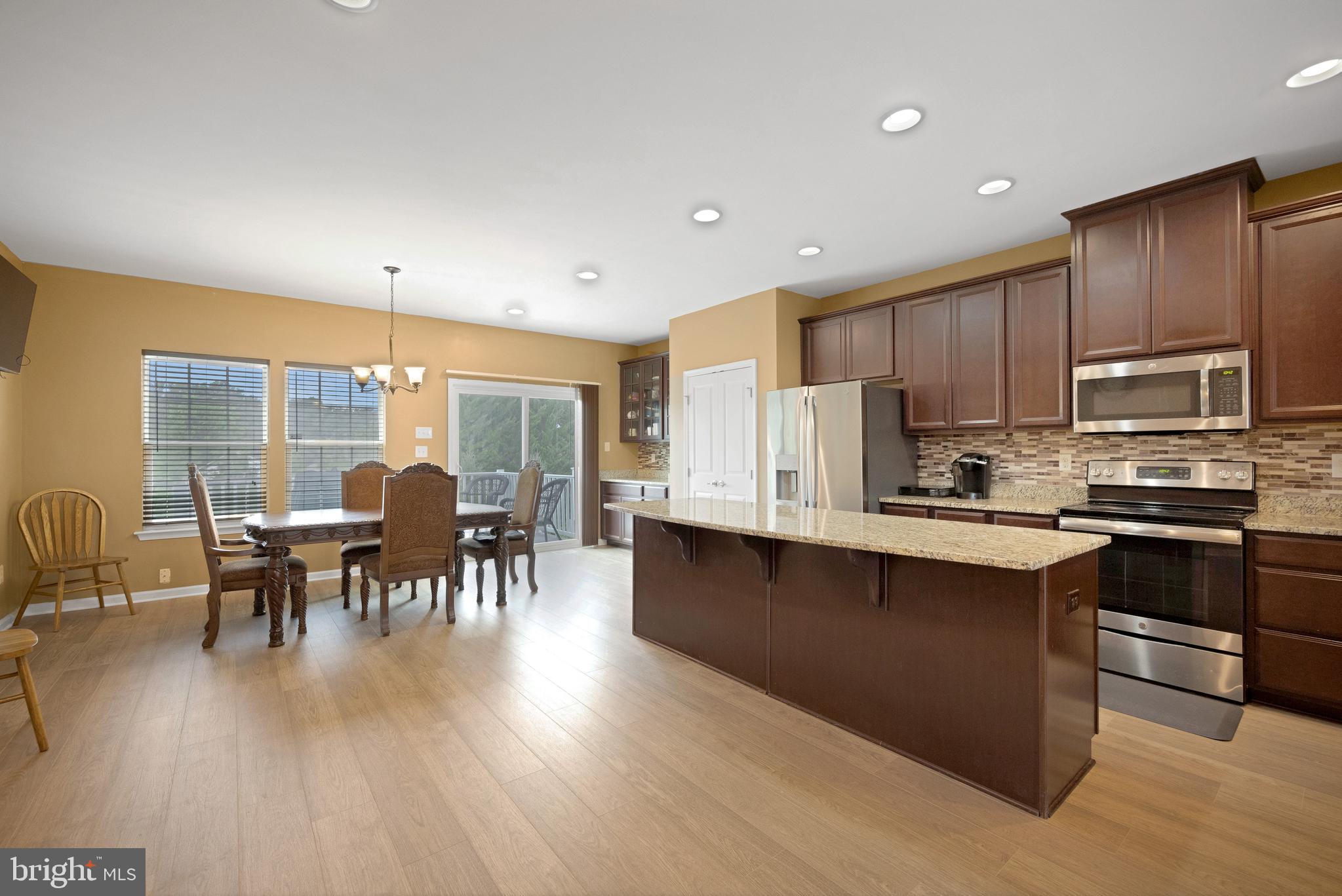 1072 Prime Place Sewell, NJ 08080 - Photo 10 of 36 a kitchen with stainless steel appliances granite countertop a stove top oven a sink dishwasher a dining table and chairs with wooden floor