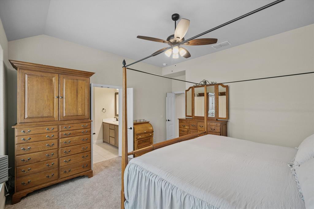 4102 Sublett Way Kaufman, TX 75142 - Photo 31 of 40 Bedroom with vaulted ceiling, light colored carpet, ceiling fan, ensuite bath, and light tile patterned flooring
