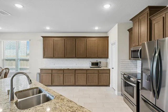 a kitchen with stainless steel appliances granite countertop a sink a stove and a refrigerator