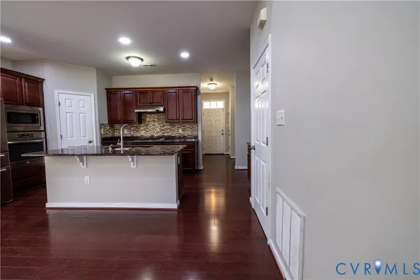 a view of a kitchen with kitchen island white cabinets and stainless steel appliances