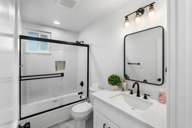 a bathroom with a shower sink vanity mirror and toilet