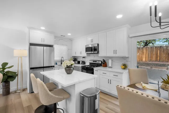 a kitchen with stainless steel appliances a stove a sink a microwave a refrigerator cabinets and dining table