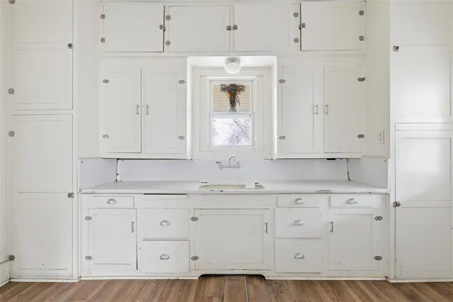a room with granite countertop white cabinets and wooden floors