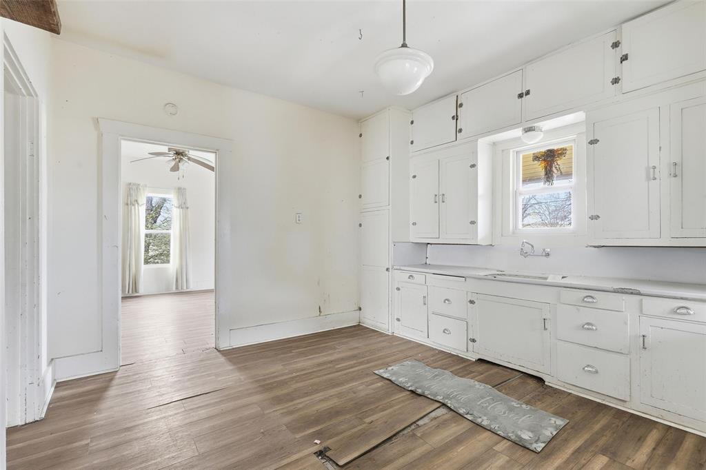 403 East Morgan Street Meridian, TX 76665 - Photo 19 of 40 a room with granite countertop white cabinets and wooden floors