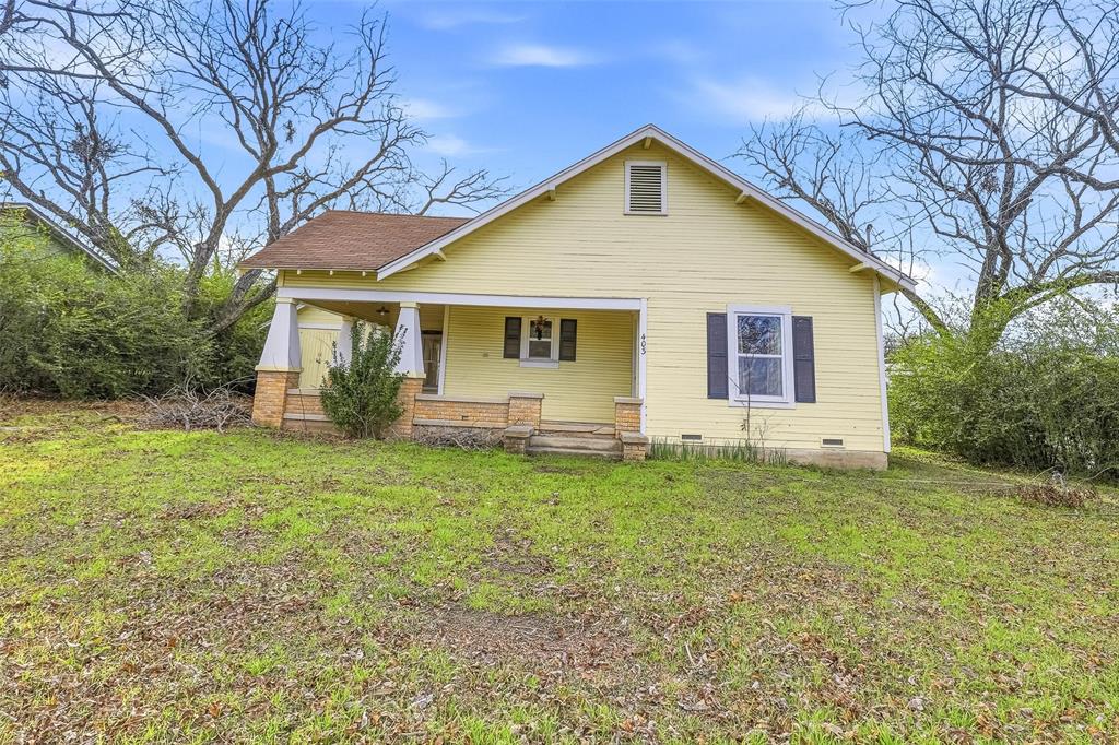 403 East Morgan Street Meridian, TX 76665 - Photo 2 of 40 a view of a yard in front of a house with plants and large tree