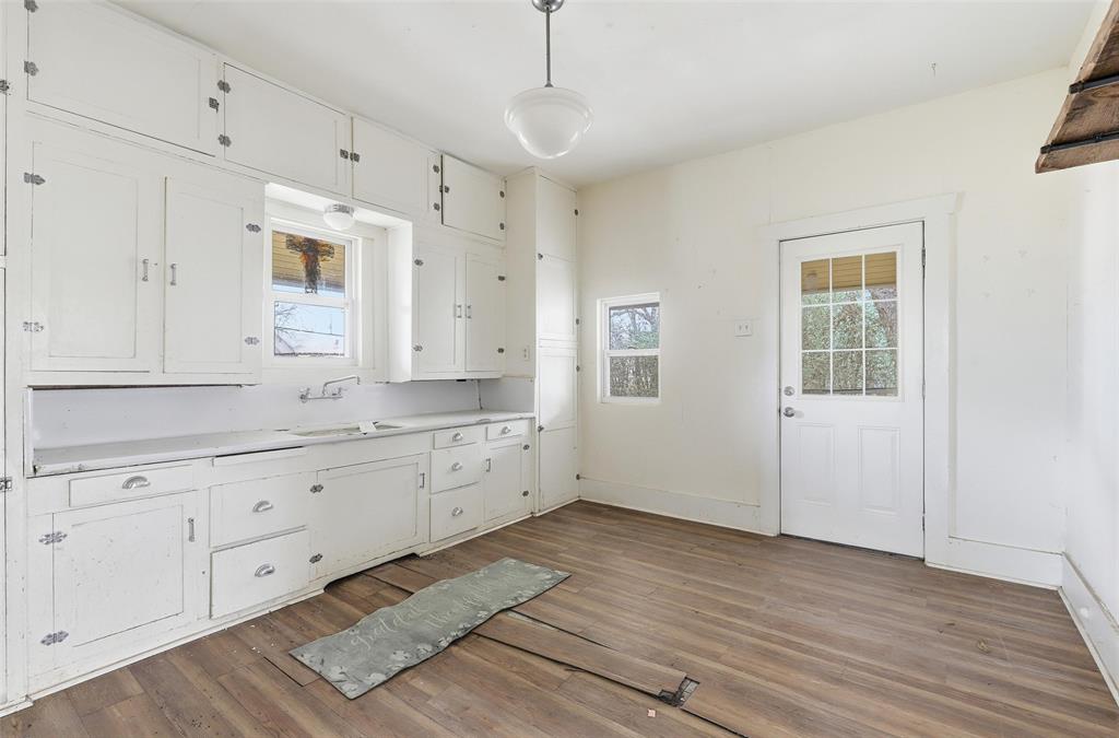 403 East Morgan Street Meridian, TX 76665 - Photo 21 of 40 a large white kitchen with granite countertop white cabinets and a wooden floor