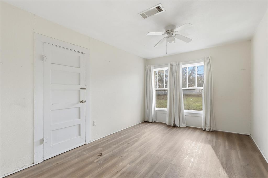 403 East Morgan Street Meridian, TX 76665 - Photo 26 of 40 an empty room with wooden floor fan and windows