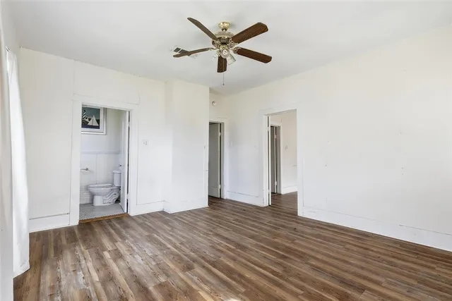 a view of empty room with wooden floor and ceiling fan