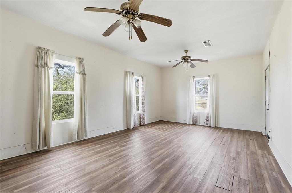 403 East Morgan Street Meridian, TX 76665 - Photo 35 of 40 an empty room with wooden floor chandelier fan and windows
