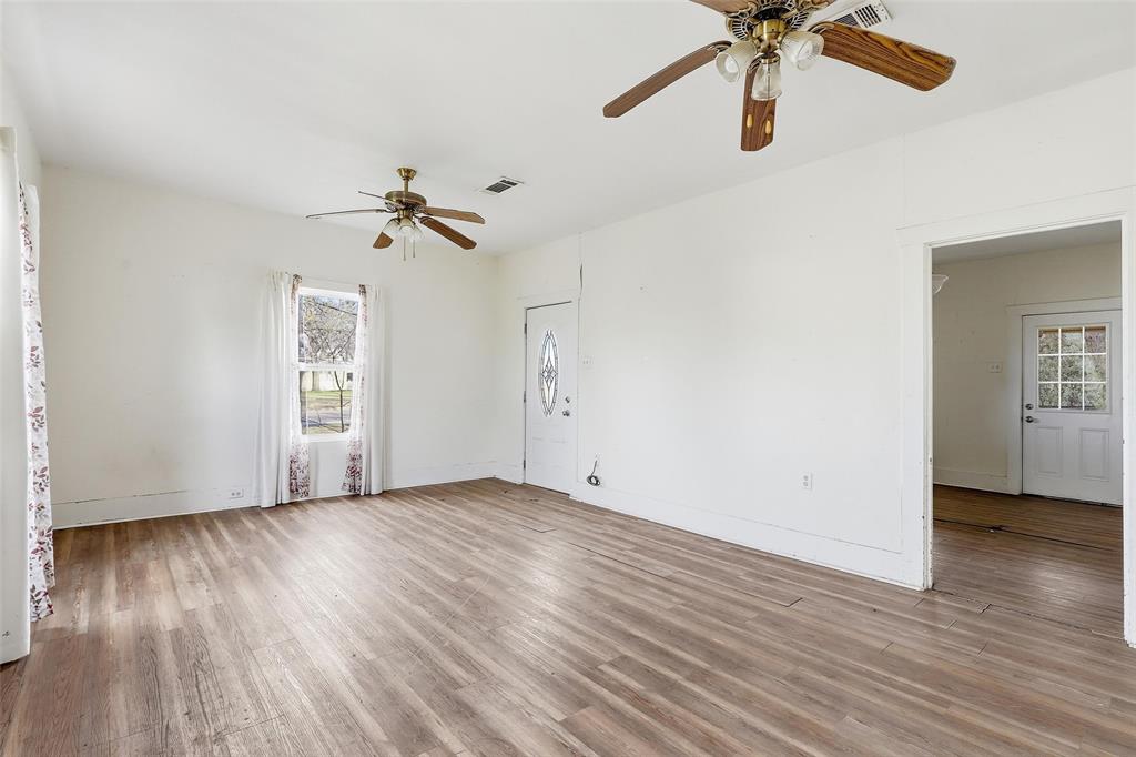 403 East Morgan Street Meridian, TX 76665 - Photo 37 of 40 an empty room with wooden floor chandelier fan and windows