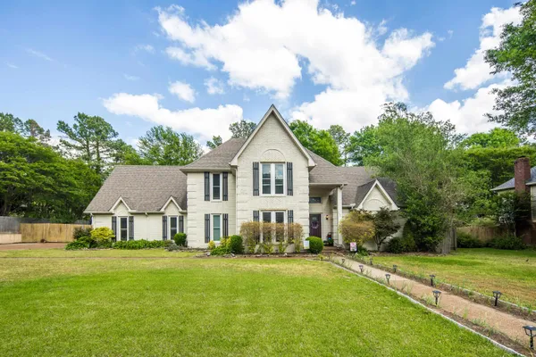 a view of a white house with a big yard and large trees