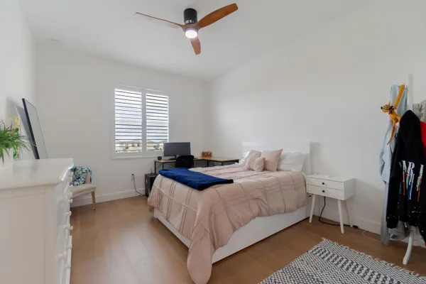 a bedroom with a bed and a potted plant on the dresser