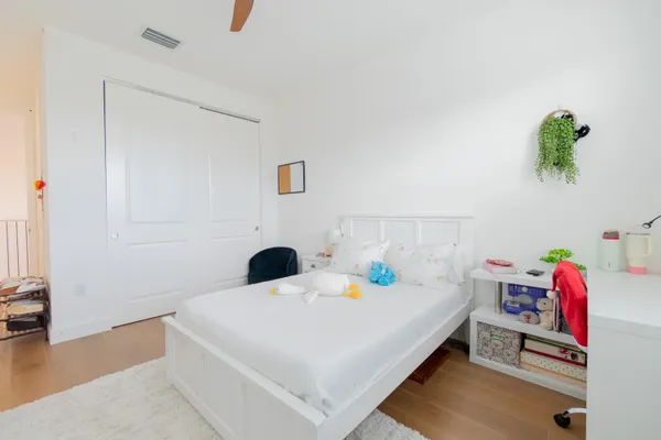 a bedroom with a bed a potted plant and a window