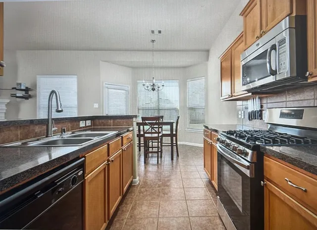 a kitchen with stainless steel appliances granite countertop a stove a sink and a microwave