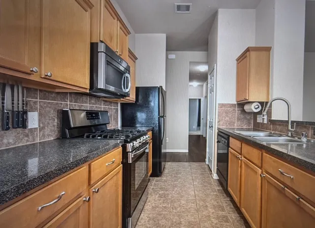 a kitchen with stainless steel appliances granite countertop a stove a sink and a refrigerator