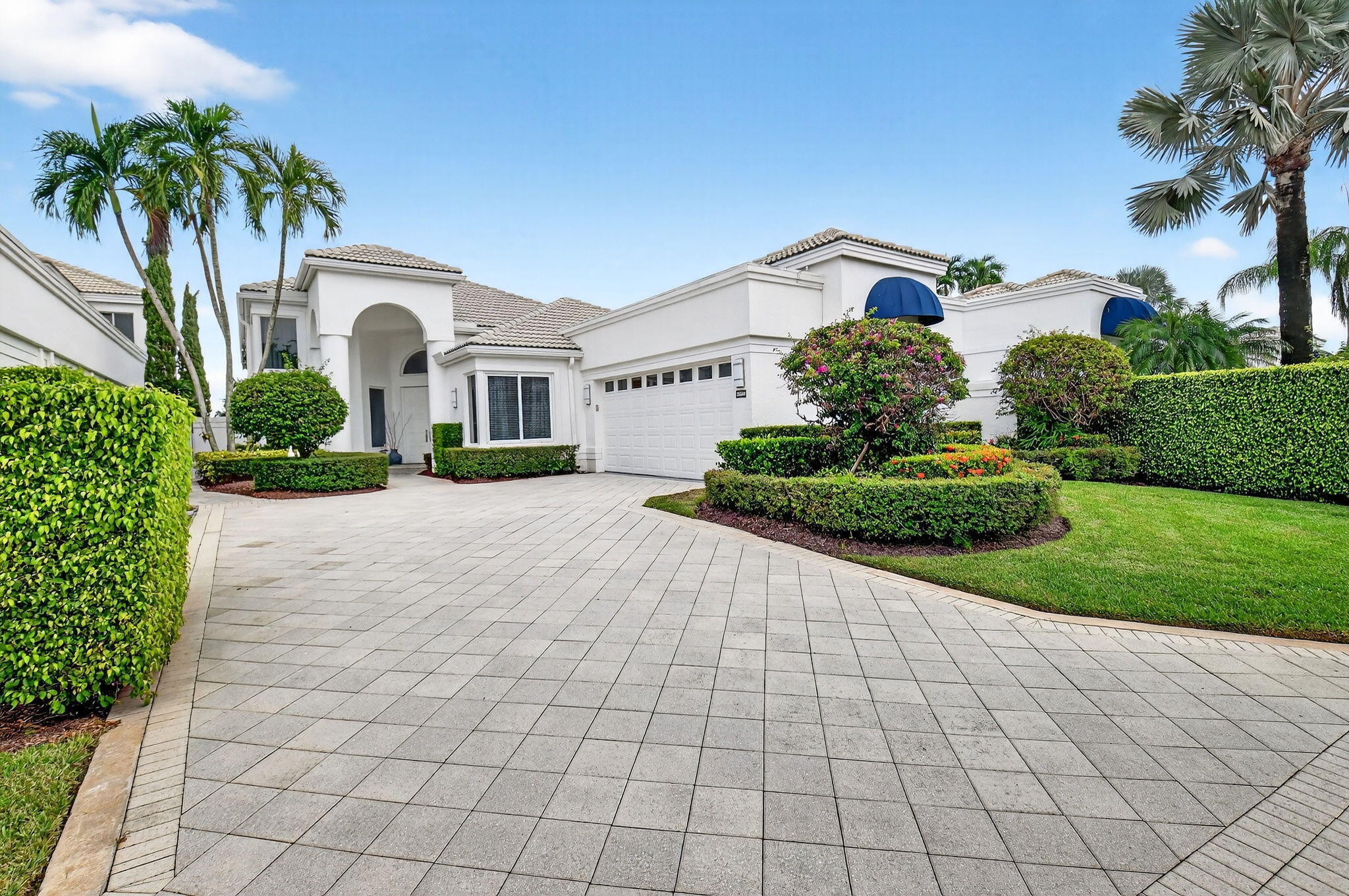 2563 Northwest 63rd Street Boca Raton, FL 33496 - Photo 1 of 65 a view of a white house with a yard and potted plants