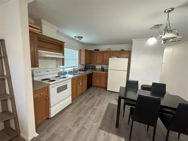 a kitchen with a refrigerator a stove top oven a sink dishwasher and white cabinets with wooden floor