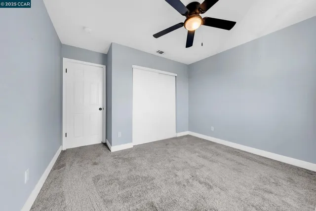 an empty room with chandelier fan