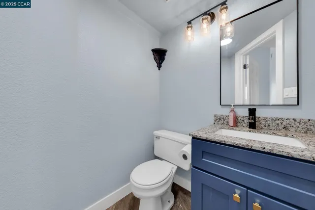 a bathroom with a granite countertop toilet sink and mirror