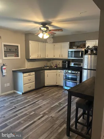 a kitchen with stainless steel appliances granite countertop a stove top oven a sink and dishwasher a refrigerator with wooden floor