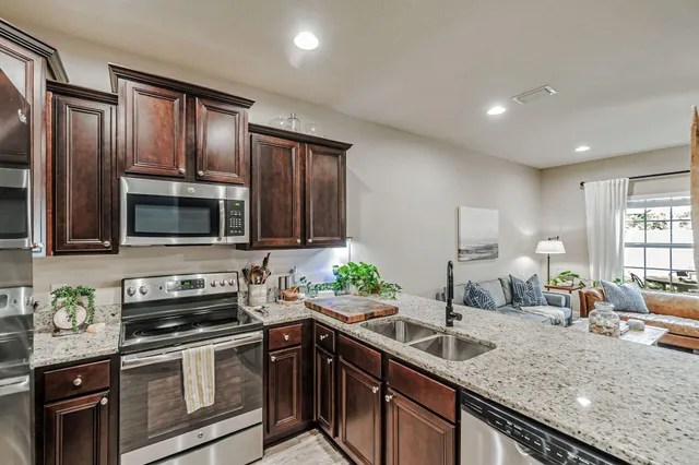 a kitchen with granite countertop stainless steel appliances a stove sink and cabinets