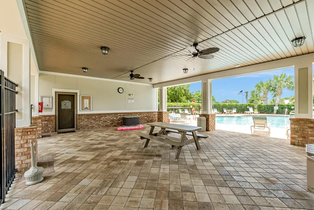 a view of swimming pool with seating area and trees in the background