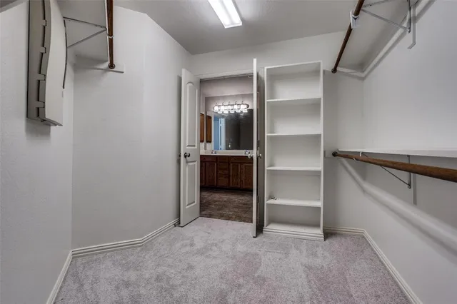 an empty room with a chandelier fan and windows