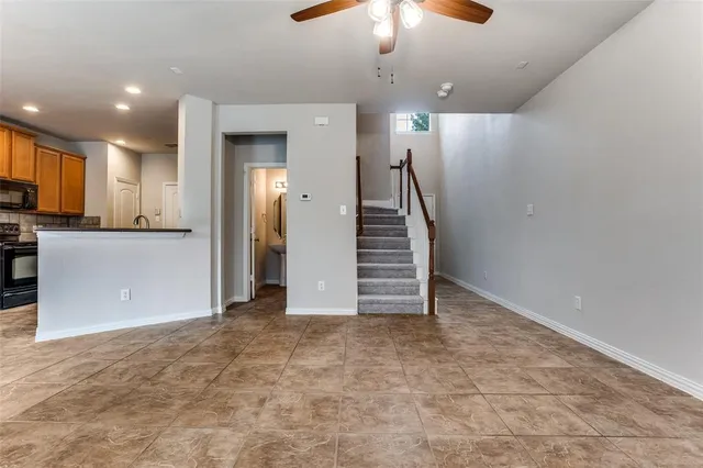 an empty room with a kitchen and a chandelier fan