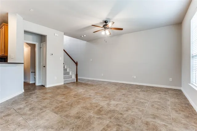 an empty room with chandelier fan and windows