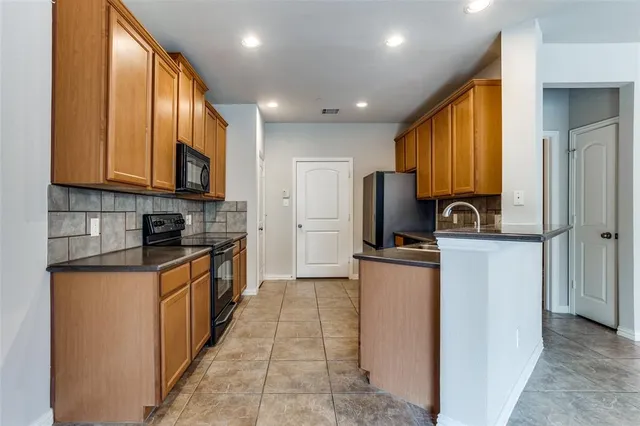 a kitchen with stainless steel appliances granite countertop a refrigerator a stove top oven a sink and dishwasher