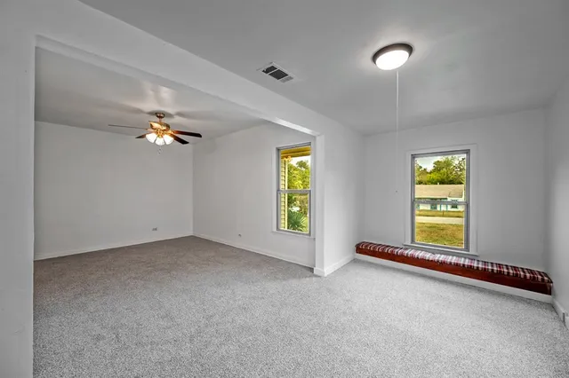 an empty room with windows and chandelier fan