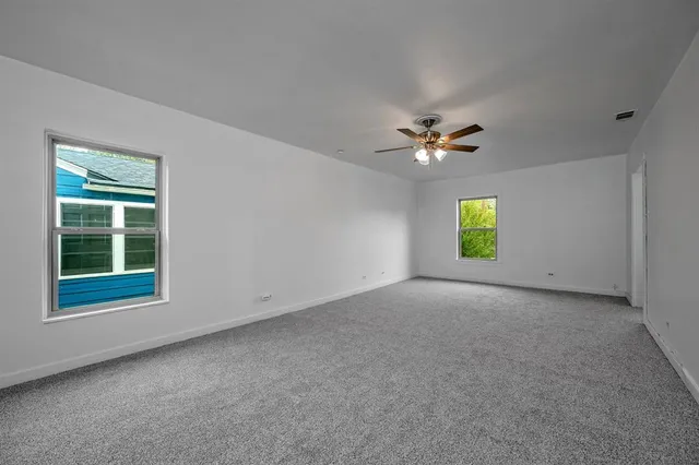 an empty room with a window and a ceiling fan
