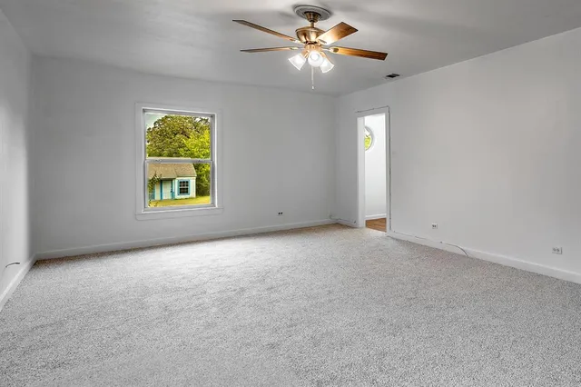 an empty room with windows and ceiling fan