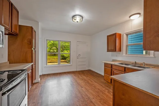 a kitchen that has a sink a stove and wooden floor