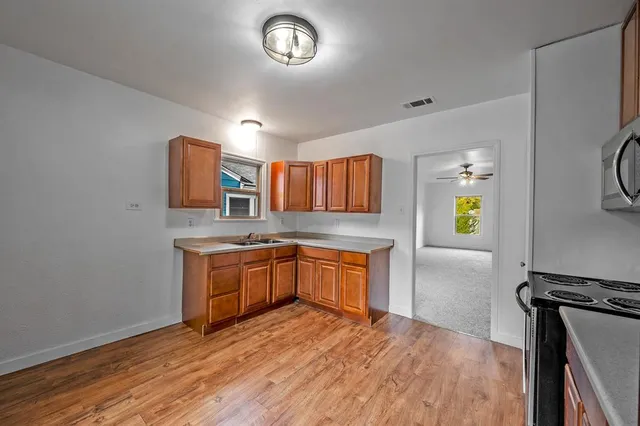 a kitchen with stainless steel appliances granite countertop a sink a stove top oven a chimney and a center island