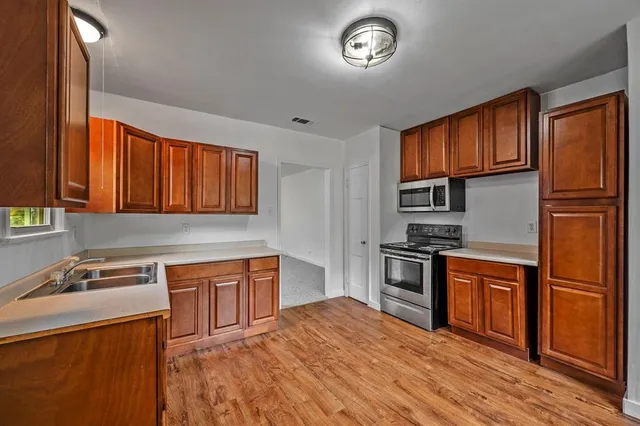 a kitchen with stainless steel appliances granite countertop a refrigerator a sink dishwasher and wooden cabinets with wooden floor