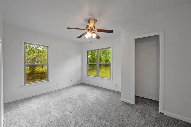 an empty room with windows and fan