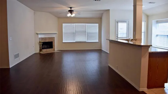 an empty room with wooden floor fireplace and windows