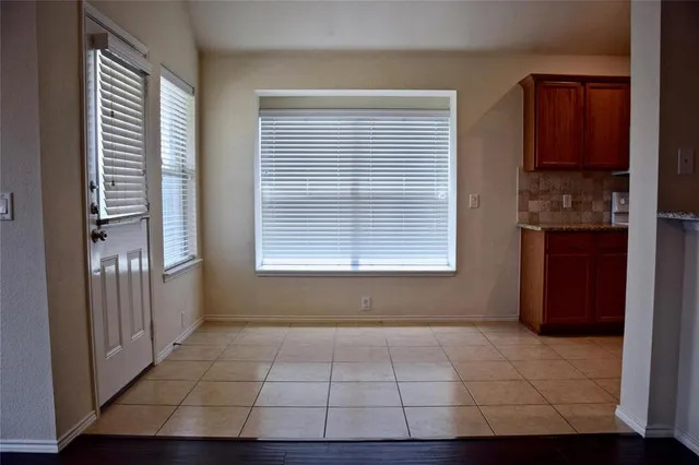 a view of an empty room with wooden floor a fireplace and a window