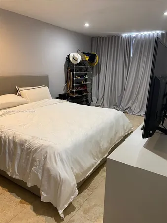 a bedroom with a bed and a flat tv screen on the dresser