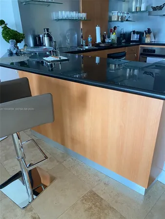 a kitchen with granite countertop a sink dishwasher a stove and a dining table with wooden floor