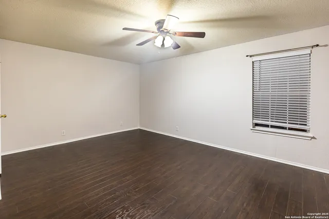 a view of a room with wooden floor and a ceiling fan