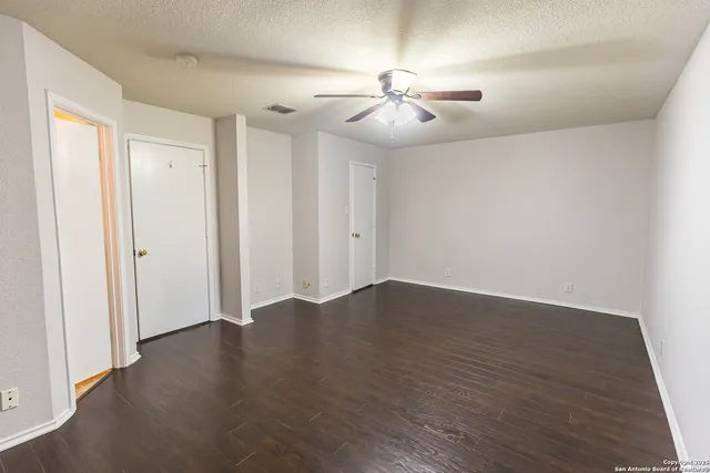 an empty room with wooden floor chandelier fan and closet area