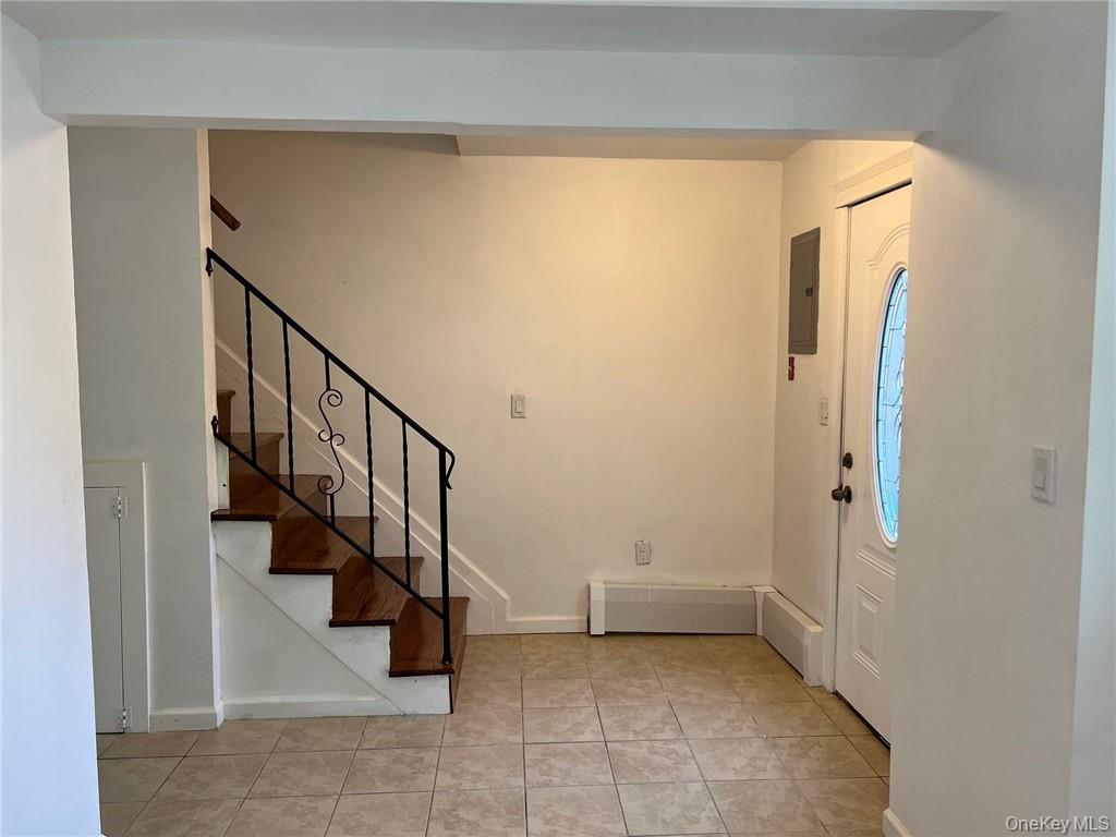Foyer entrance featuring electric panel and light tile patterned flooring and stairs leading to the second floor