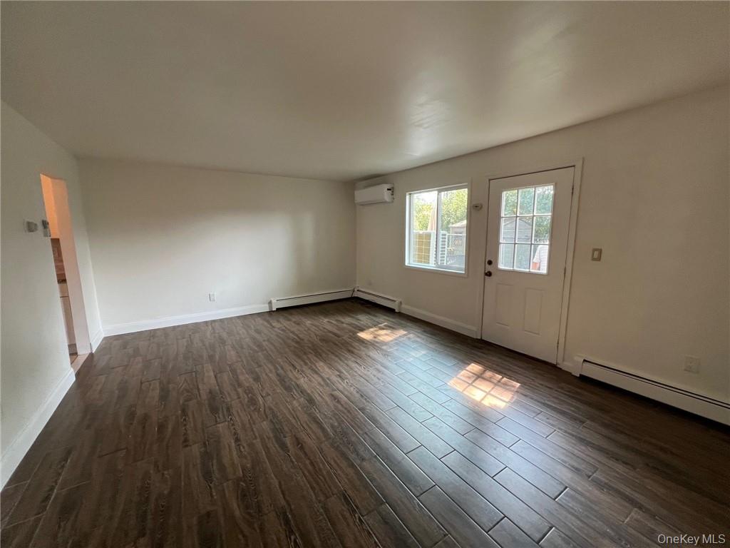 38 Hampton Court Middletown, NY 10941 - Photo 4 of 17 Dining room/living room combination with a wall mounted AC, baseboard heating, and dark hardwood / wood-style flooring