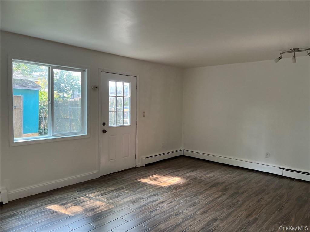 38 Hampton Court Middletown, NY 10941 - Photo 5 of 17 Part of living room/dining area with a door to the backyard. Baseboard heating and dark hardwood / wood-style floors