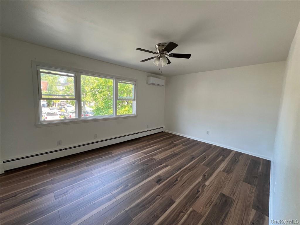 38 Hampton Court Middletown, NY 10941 - Photo 9 of 17 Bedroom #1 room featuring a wall mounted AC, a baseboard heating unit, ceiling fan, and dark hardwood / wood-style floors