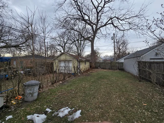 a view of a backyard that has plants and trees with wooden fence