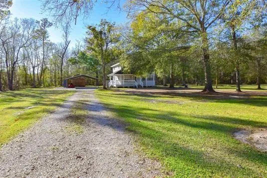 a view of a house with a big yard and large trees